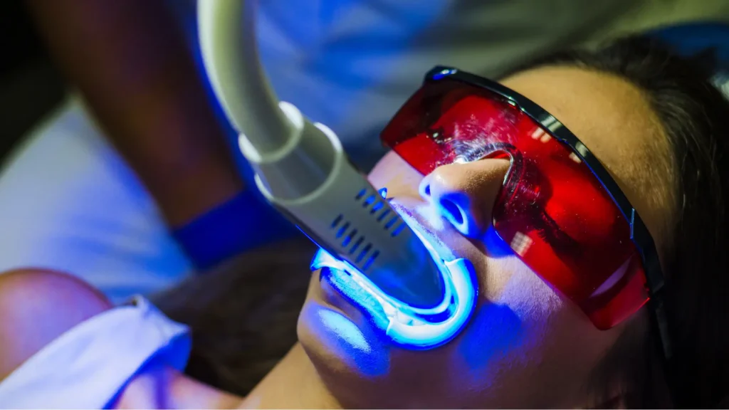 Dentist applying blue curing light during a dental procedure